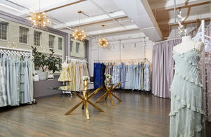 Dessy's New York showroom with dress racks, fitting areas and gold chairs.